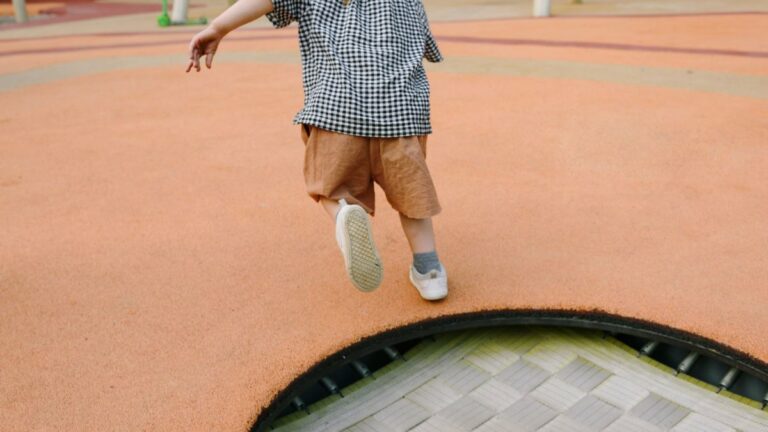 A child running towards a trampoline on a playground